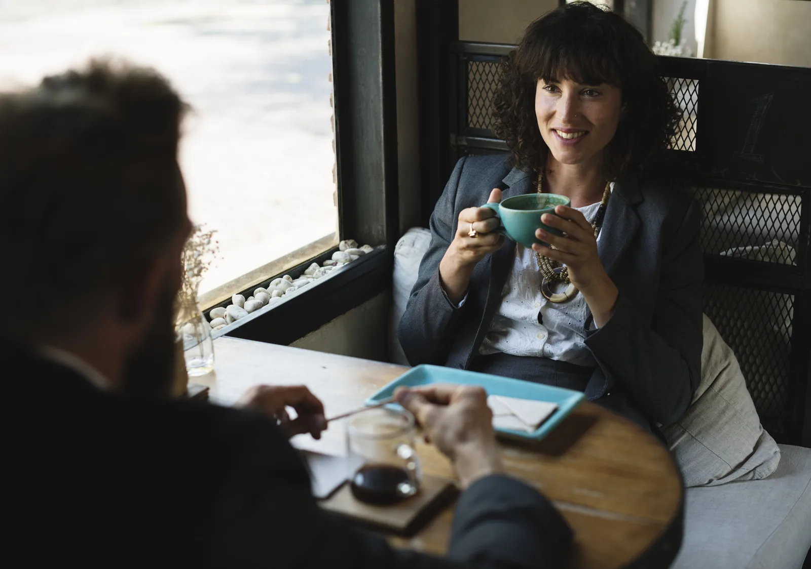 Dos profesionales conversando en una cafetería con portátiles